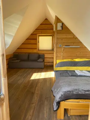 a room with a bed and a couch in a attic at Tabacówka in Tabaszowa