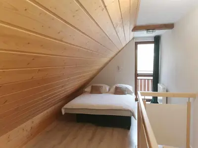 a bed in a room with a wooden ceiling at PrzyStań w Gorcach in Konina