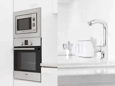 a white kitchen with a microwave and a sink at Snow White Apartment in Kraków