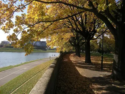 a park with trees and a sidewalk next to a river at Snow White Apartment in Kraków