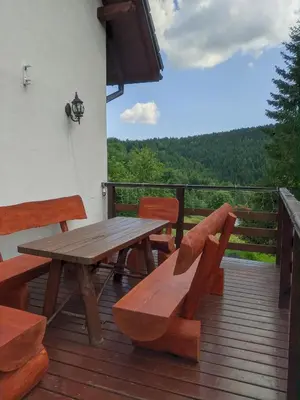 a wooden picnic table and benches on a deck at Zacisze na Wzgórzu in Zawoja