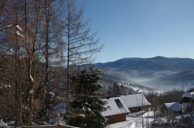 a snow covered cabin with a christmas tree in the foreground at Zacisze na Wzgórzu in Zawoja