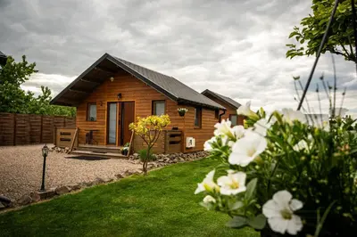 a wooden cabin with a yard with flowers at Relax domki Zator in Zator