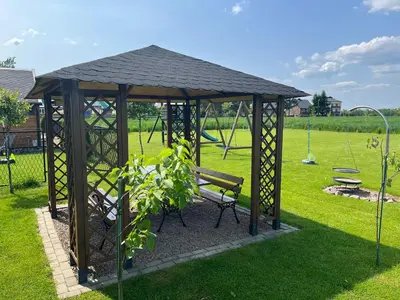 a wooden gazebo with a bench in a park at Relax domki Zator in Zator