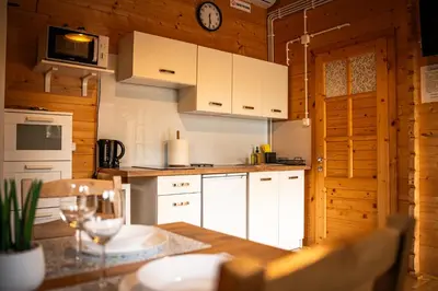 a kitchen with white cabinets and a clock on the wall at Relax domki Zator in Zator