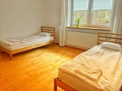 two beds in a room with wooden floors and a window at Uroczy dom i bezpłatny parking in Mników