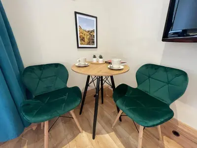 a table and two green chairs in a room at Aparthotel Cracow in Kraków