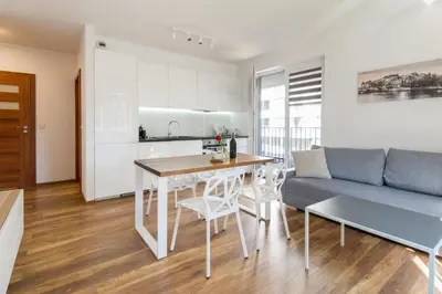 a kitchen and a living room with a table and a couch at Perfect Stay Zabłocie 35 in Kraków