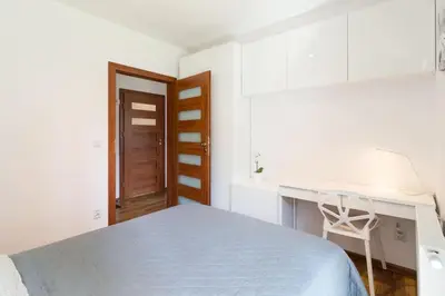 a white bedroom with a bed and a desk at Perfect Stay Zabłocie 35 in Kraków
