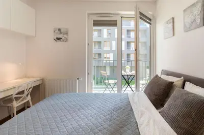 a bedroom with a bed and a desk and a balcony at Perfect Stay Zabłocie 35 in Kraków