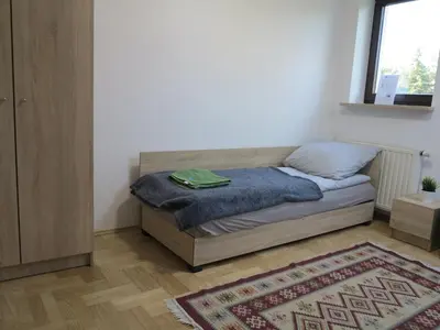 a bedroom with a bed with a blue blanket and a rug at AirSpot Balice in Cholerzyn