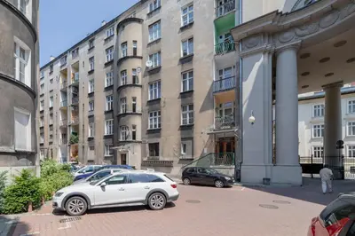 a white car parked in front of a large building at Spacious Retro Apartment in the Center of Cracow by Noclegi Renters in Kraków