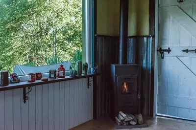a wood stove in a room with a window at RESETówka nr 1 - chatka na odludziu z mega widokami & leśne SPA in Jaszczurowa