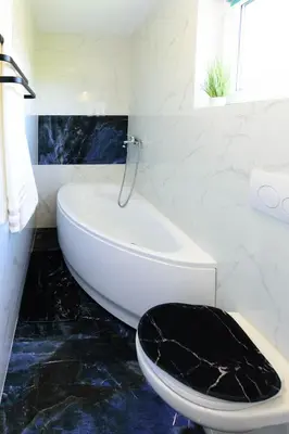a bathroom with a white tub and a black toilet at Domek na wzgórzu in Sosnowice