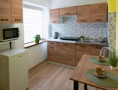 a kitchen with wooden cabinets and a wooden table at Domek na wzgórzu in Sosnowice