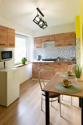 a kitchen with wooden cabinets and a table and chairs at Domek na wzgórzu in Sosnowice