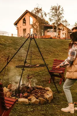 a woman is standing next to a fire at Domki Bliżej Natury z Jacuzzi in Rabka