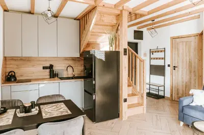 a kitchen with a refrigerator and a table in a room at Domki Bliżej Natury z Jacuzzi in Rabka