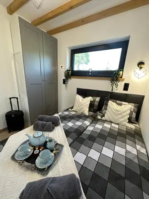 a room with two beds and a table with dishes on it at Domki Bliżej Natury z Jacuzzi in Rabka