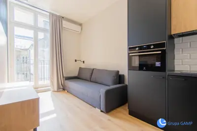 a living room with a couch and a kitchen at Apartamenty Skawińska 10 in Kraków