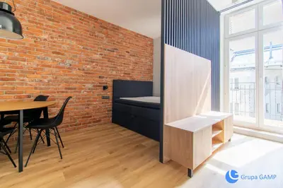 a room with a brick wall and a table and chairs at Apartamenty Skawińska 10 in Kraków