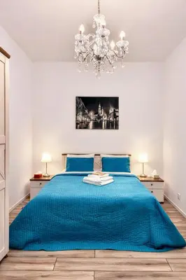 a bedroom with a blue bed with a chandelier at Z-1 Kraków Old Town O&P ApartFamily in Kraków