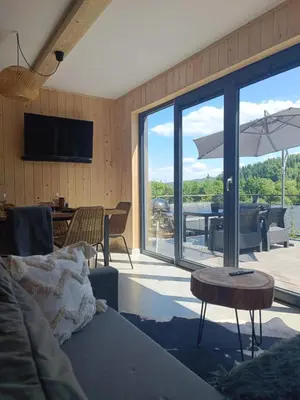 a living room with a couch and a table with an umbrella at Mucharskie Stodoły Stodoła II - Garden Spa in Jaszczurowa