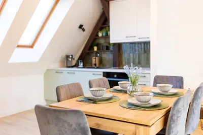 a kitchen and dining room with white cabinets and a wooden table at Apartment with Entresol Old Town Krakow in Kraków