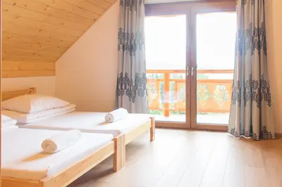 a bedroom with two beds and a large window at Domki w Kasinie in Kasina Wielka