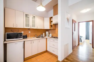 a kitchen with white cabinets and a microwave at Apartment Krakowska City Center WAWELOFTS in Kraków