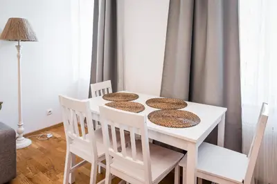 a white dining room table with four chairs and a white table withmbermbermber at Apartment Krakowska City Center WAWELOFTS in Kraków