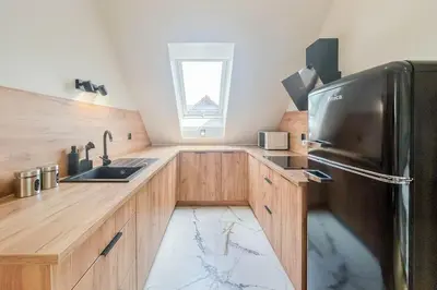 a kitchen with wooden cabinets and a black refrigerator at Apartament Ptasi Śpiew 2 in Rabka