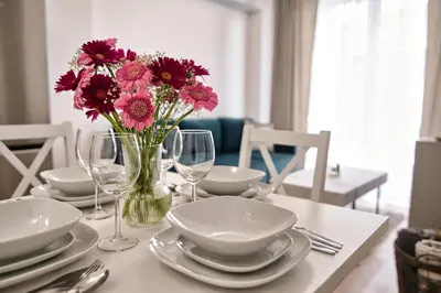 a table with plates and a vase of flowers on it at Apartament Lider 41 by Housine in Zator
