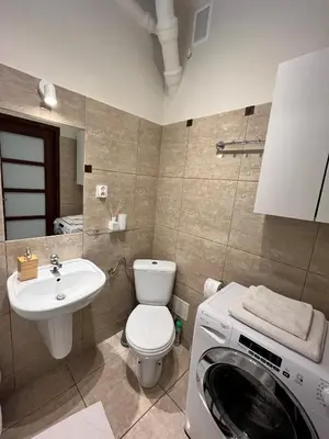 a bathroom with a washing machine and a sink at Apartament Globtroter in Kraków