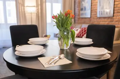 a dining room table with plates and a vase of flowers at Lux apartmenty - Old City Kraków in Kraków