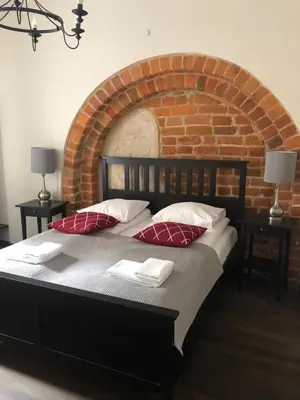 a large bed in a room with a brick wall at Lux apartmenty - Old City Kraków in Kraków