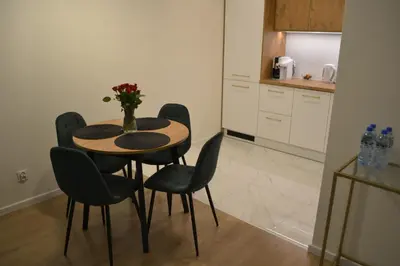 a kitchen with a table with chairs and a vase of flowers at Apartament Aktorów Bronowice in Kraków