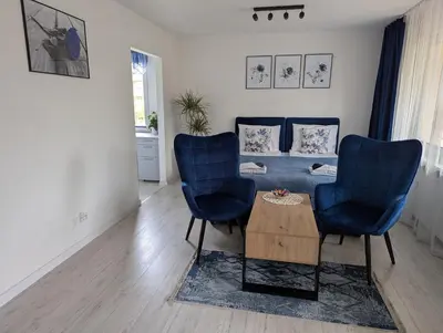 a living room with two blue chairs and a couch at Apartament Piccolo in Kraków