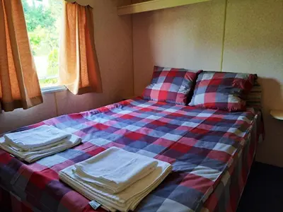 a bed with a checkered blanket and a window at Pensjonat Łysa Góra in Zator