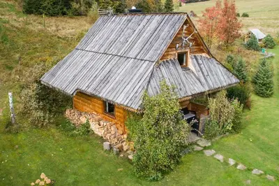 an old house with a metal roof on a field at Domek w górach SmoLenisko in Nowy Targ