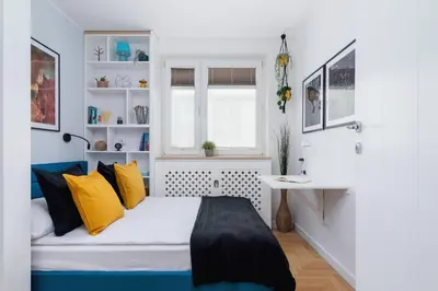 a bedroom with a bed with yellow pillows and a desk at Cozy Apartment Bartla 19 by Noclegi Renters in Kraków