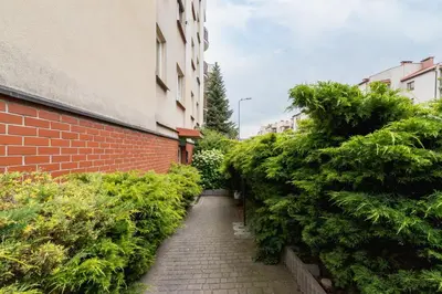 a brick alley way with bushes next to a building at Cozy Apartment Bartla 19 by Noclegi Renters in Kraków
