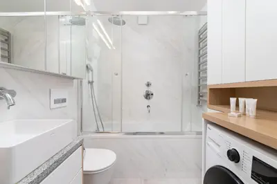 a white bathroom with a shower and a toilet at Cozy Apartment Bartla 19 by Noclegi Renters in Kraków