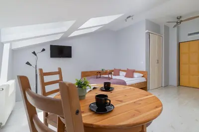 a dining room with a wooden table and a couch at Sunny Studio Mostowa Krakow Kazimierz by Nolegi Renters in Kraków