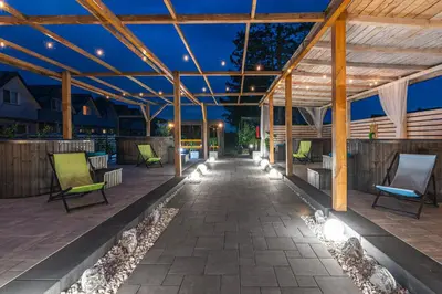 an outdoor patio with chairs and lights at night at Old Tree Home & Restaurant in Oświęcim
