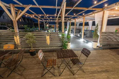 a patio with chairs and a wooden table and a bench at Old Tree Home & Restaurant in Oświęcim