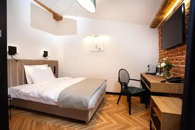 a bedroom with a bed and a desk and a television at HOTEL TEATR in Kraków