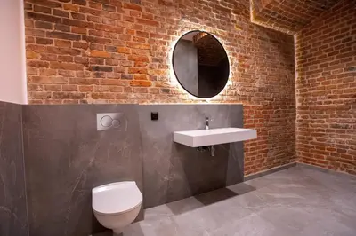 a bathroom with a toilet and a sink and a brick wall at HOTEL TEATR in Kraków