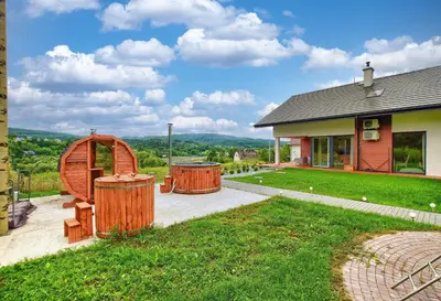 a house with two wooden barrels in the yard at ArPioNa dom nad jeziorem z jacuzzi, sauną i placem zabaw in Dąbrówka