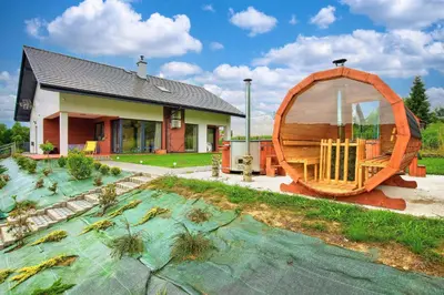 a house with a large wooden boat in the yard at ArPioNa dom nad jeziorem z jacuzzi, sauną i placem zabaw in Dąbrówka